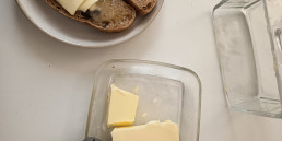 Untar mantequilla con un corta lonchas de queso. Sardinas en Lata